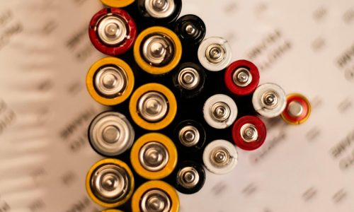 Top view of assorted batteries in an artistic arrangement on a printed surface.